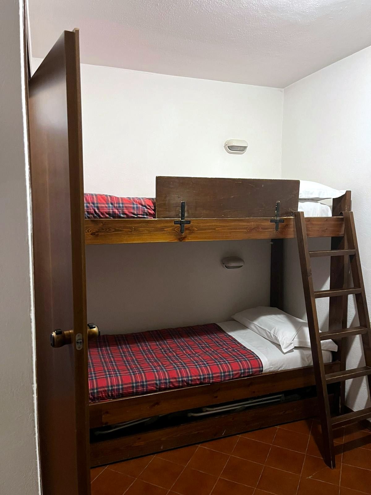 Cameretta con letto a castello in legno e coperte a quadri rossi